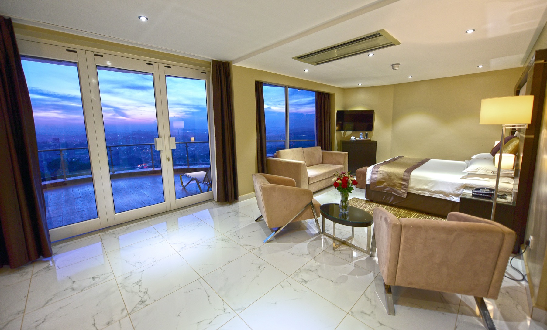 Curved wooden suite balcony with flowers and a panoramic dusk skyline