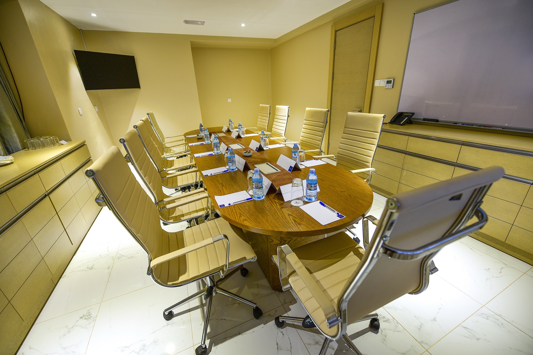 A Skyz Hotel Kampala boardroom with a marble floor and mounted TV screen
