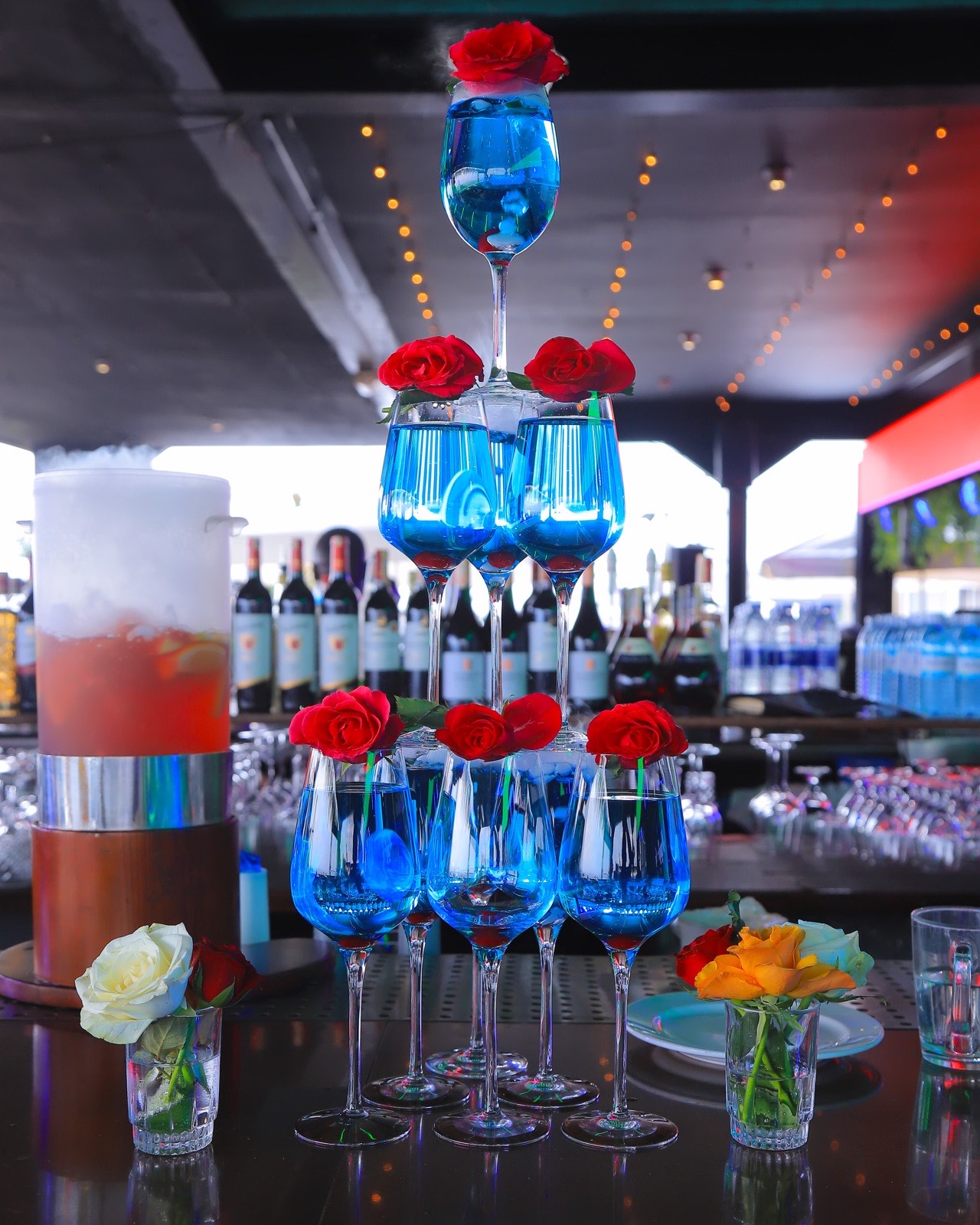 A tiered display of signature blue cocktails garnished with roses, The Kampala Style Brunch, February 2024