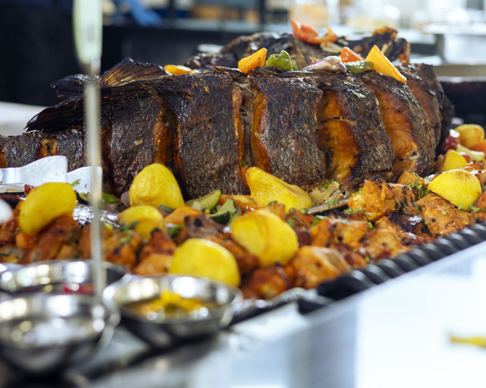 A whole roasted fish and grilled chicken spread on the buffet at The Kampala Style Brunch, July 2024