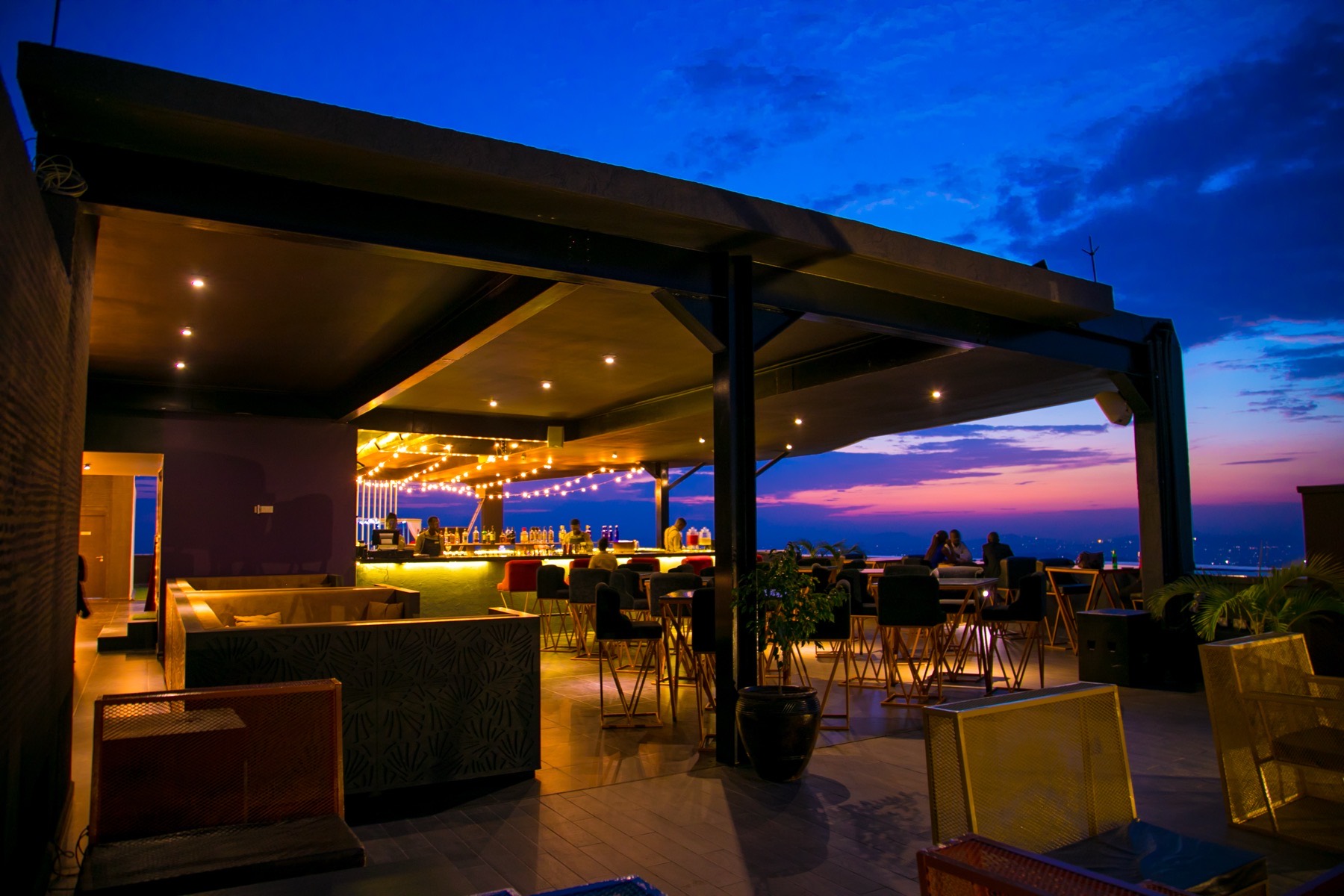 Rooftop lounge seating under a purple dusk sky above Kampala