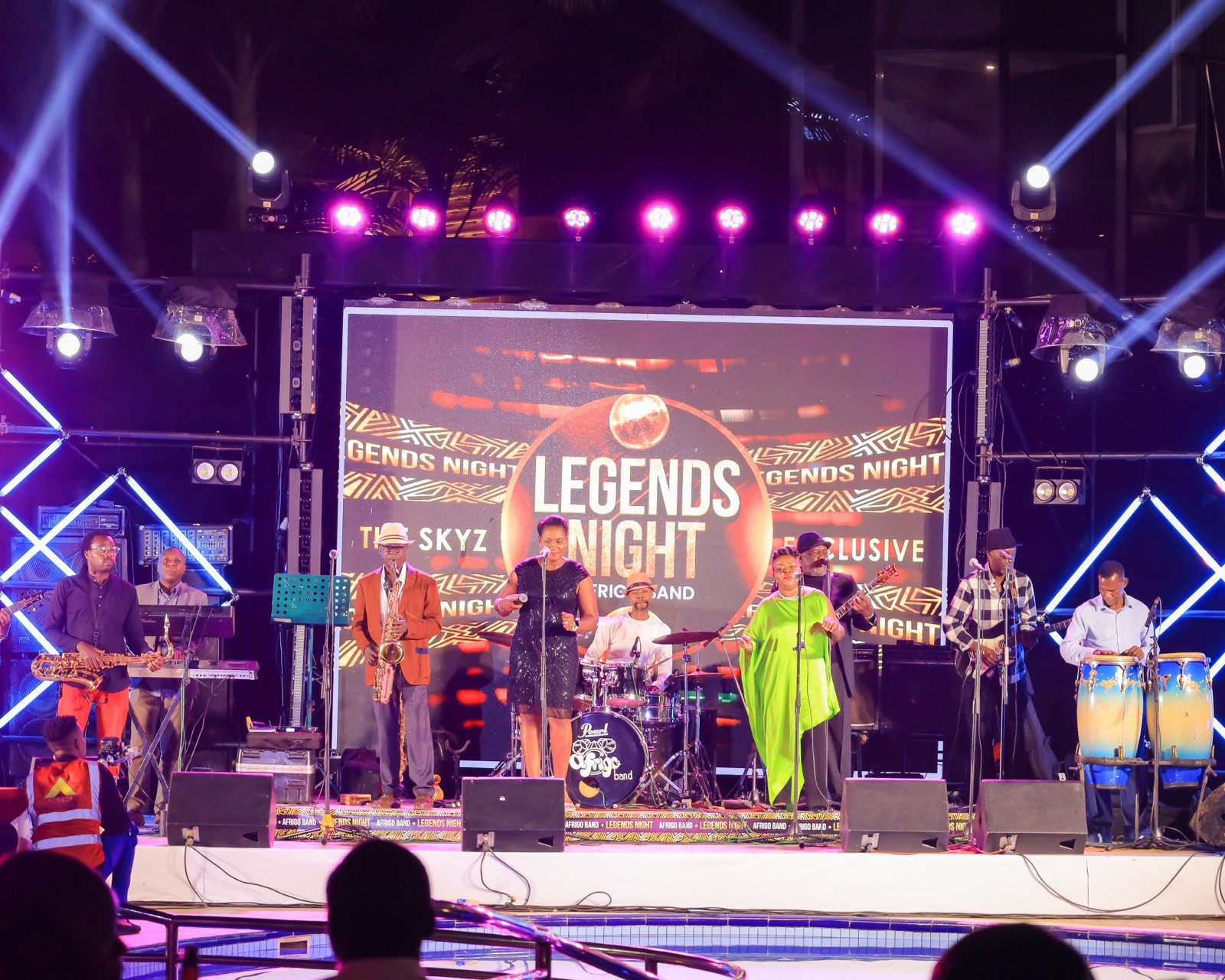 Afrigo Band performing poolside with the Legends Night screen behind them