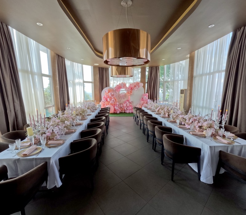The VIP Room at Skyz Hotel Kampala set up lengthwise for a birthday celebration, with a pink balloon and floral backdrop reading Happy Birthday